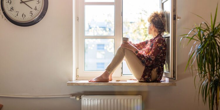 Kvinde alene med en snert af social angst, kigger ud af vinduet